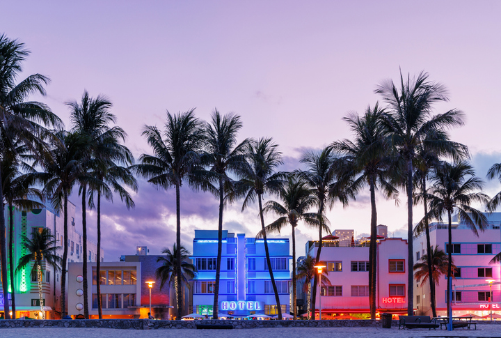 Colorful Art Deco hotels on Ocean Drive in Miami Beach glow under the warm hues of a vibrant sunset